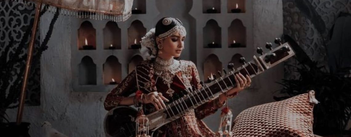 A girl adorned in Mughal-inspired jewelry plays the sitar.